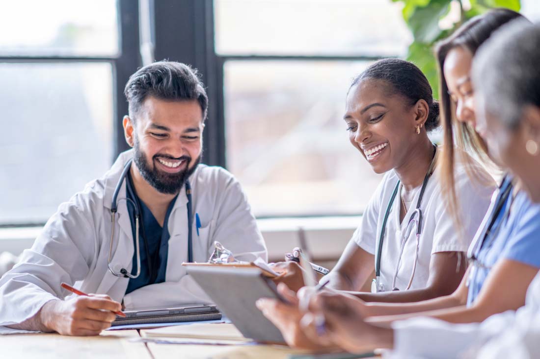 Group of diverse healthcare professionals smiling and collaborating during a meeting.