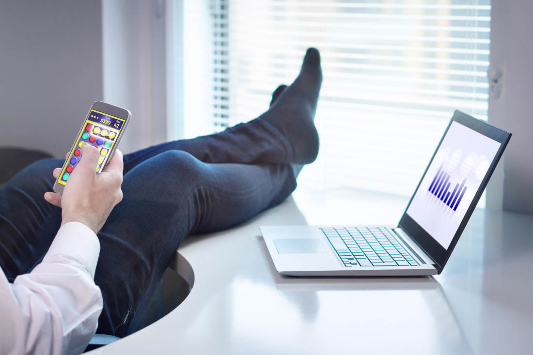 A remote employee on his phone with his feet up not working.