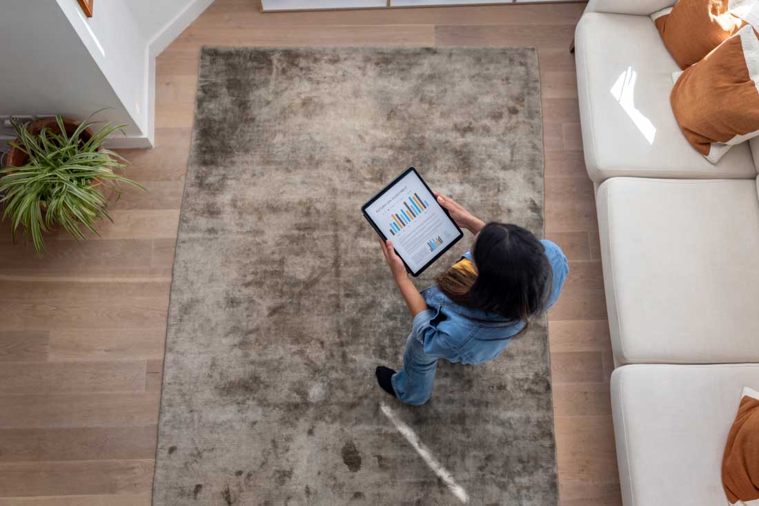 Woman reviewing charts on a tablet in a modern living room.