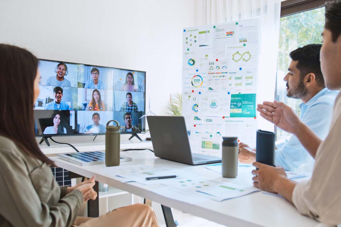 Team in hybrid meeting with video conference and presentation charts.