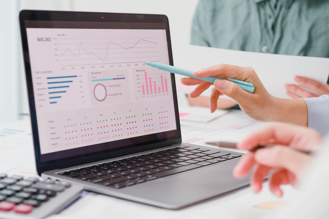 Business professionals analyzing data on a laptop screen with charts and graphs.