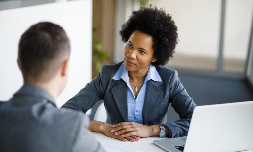 Professional job interview between a confident businesswoman and a male candidate in a modern office setting.
